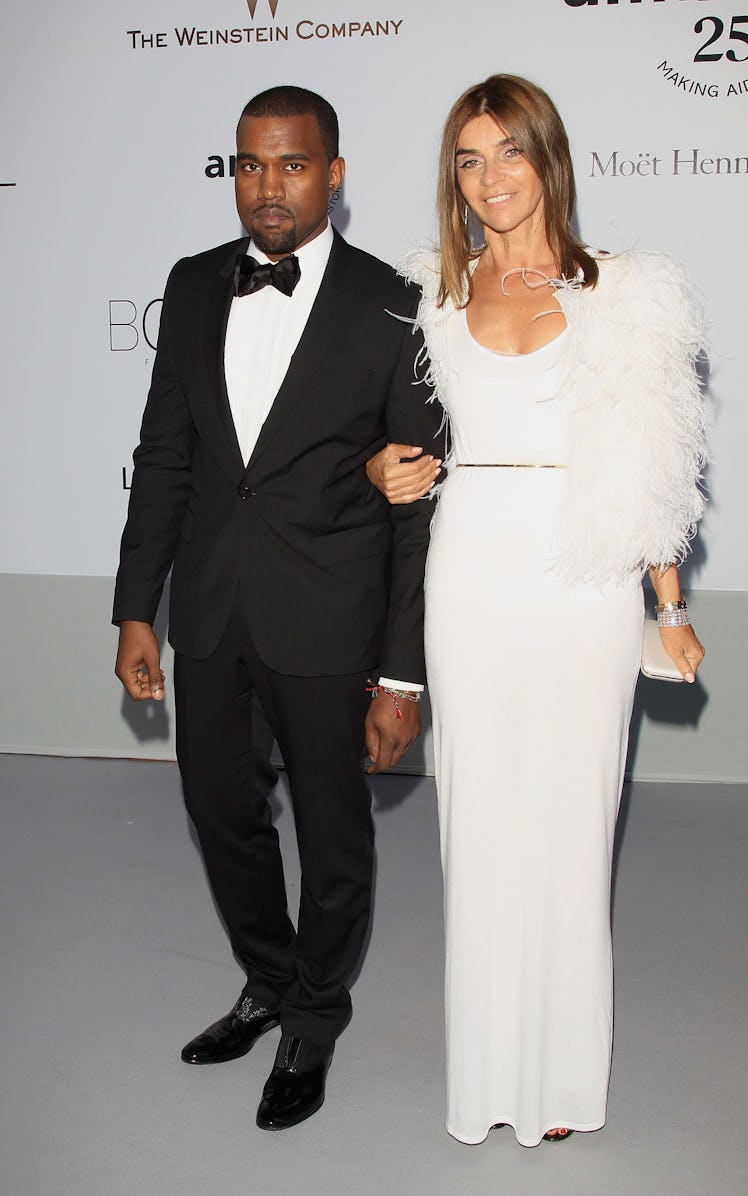 Kanye West in a black suit and white shirt and Carine Roitfeld in a white dress at the 64th Annual C...