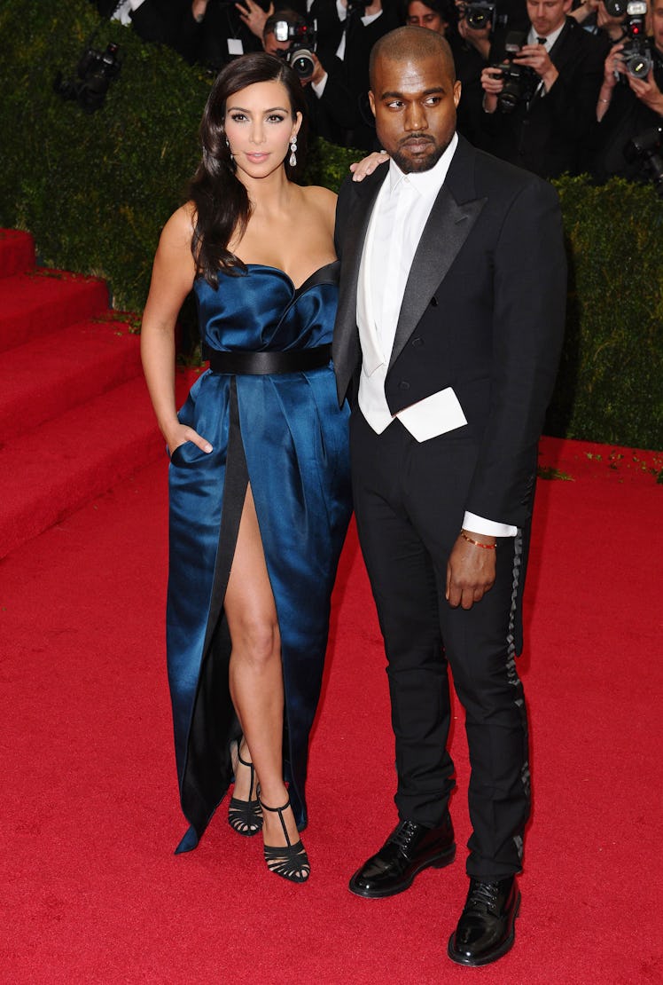 Kanye West in a black tuxedo and white shirt and Kim Kardashian in a blue gown at a red carpet event