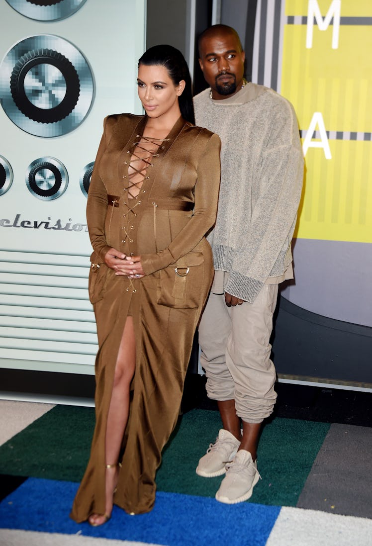 Kanye West in a beige sweater, pants and sneakers and Kim Kardashian in a tan satin dress at the MTV...