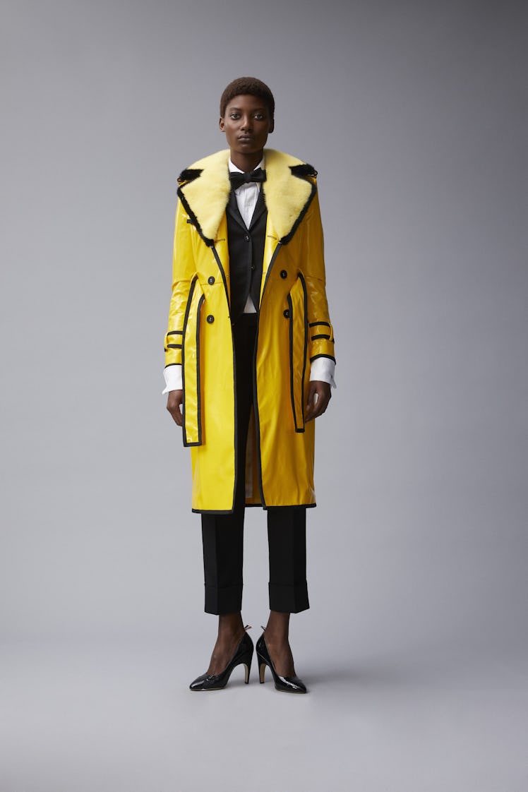 A female model posing for a photo while wearing a yellow raincoat with fur trim