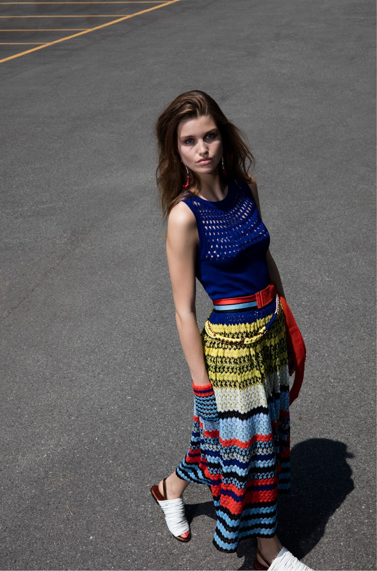 A female model walking while wearing a blue, yellow, and red striped dress