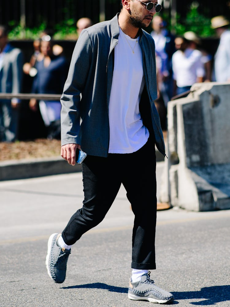 A man walking in a white shirt, grey jacket and black trousers walking