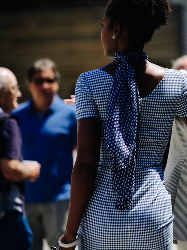 The back of a woman in a black-white polka dot dress and a scarf around her neck