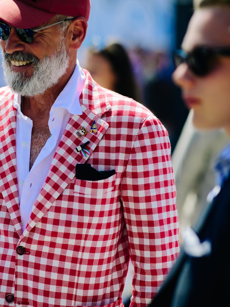 A man in a white shirt, a red cap, and a white-red checked blazer