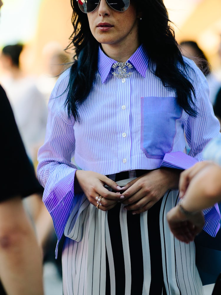A woman in a white-blue striped shirt and a black and white-striped skirt wearing black sunglasses