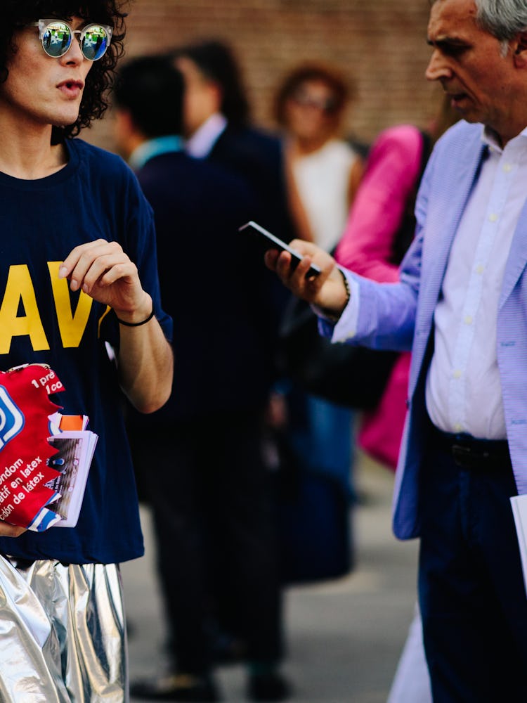 A woman in a navy shirt with print and a silver metallic skirt and a man in a white shirt, blue blaz...