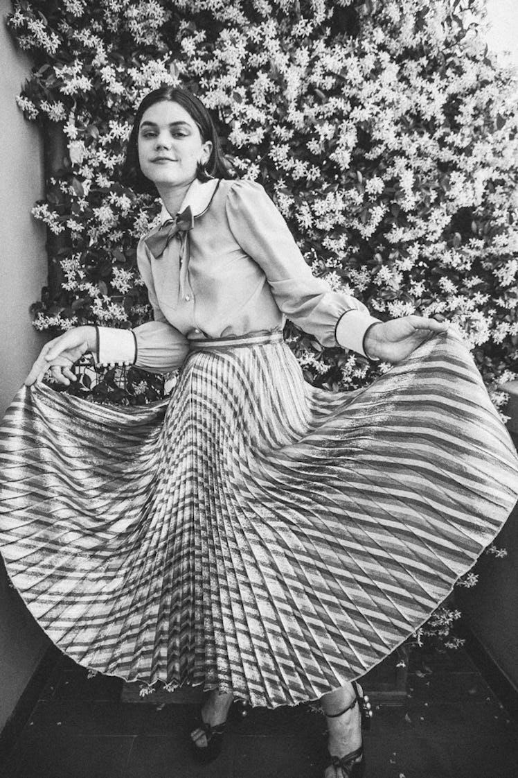 Soko posing in a pleated midi skirt at the balcony of her hotel room in Italy