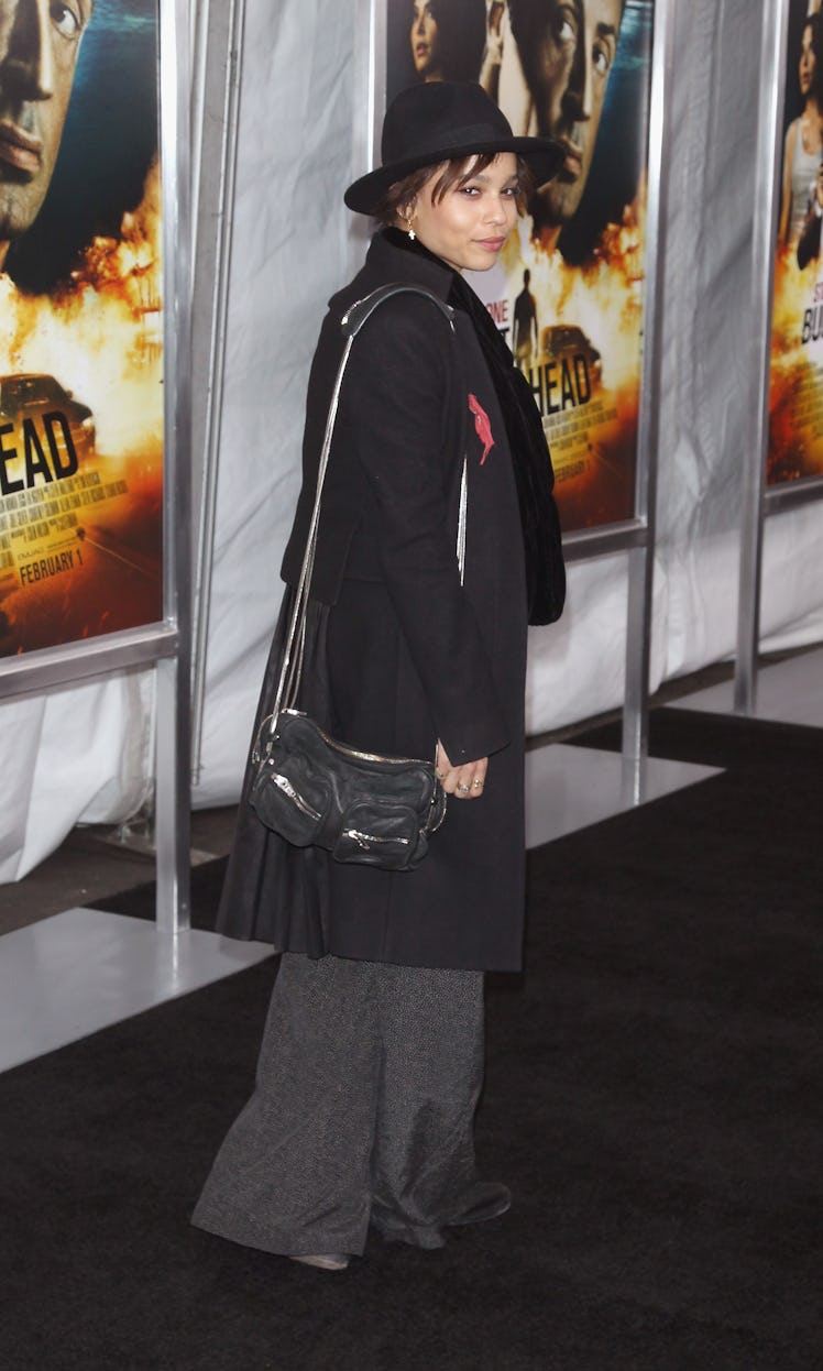 Zoe Kravitz in a black hat, black jacket and wide grey pants 