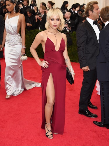 Zoe Kravitz with a short blonde hairstyle in a red gown with a slit on one leg