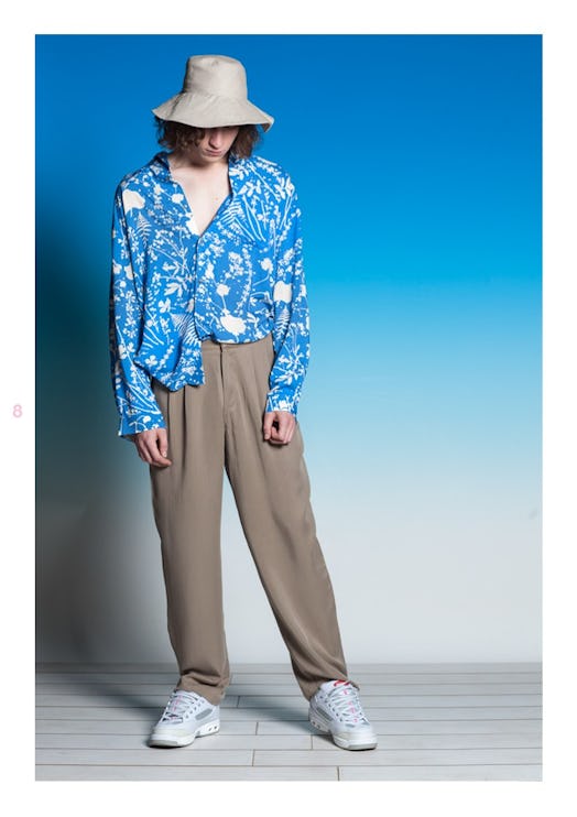 A model in a blue-white floral shirt and brown pants by Double Rainbouu standing and looking down