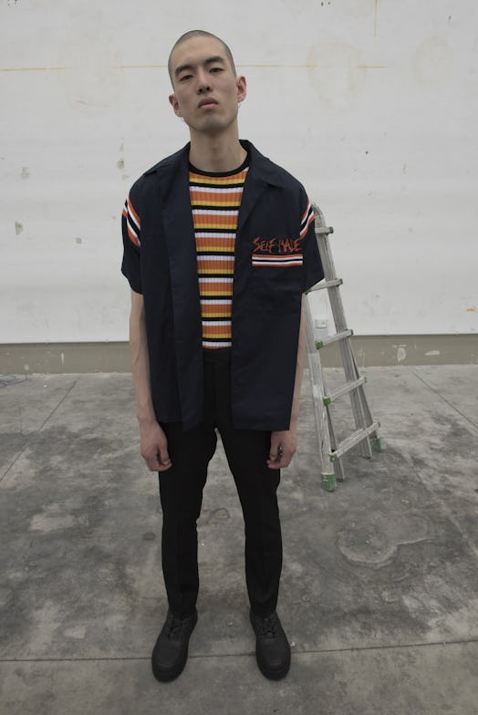 A model wearing a black waistcoat and trousers and orange-white-black striped shirt by Selfmade