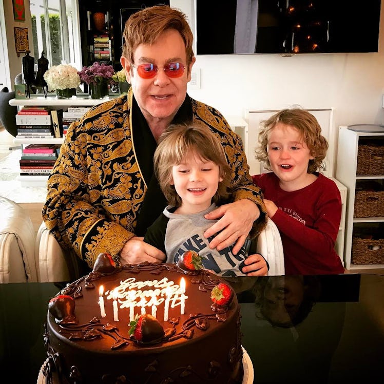 An Instagram post with Elton John in a gold-black jacket and his two sons looking at a birthday cake
