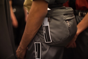 A close-up of  a grey bag worn by a model backstage at the Prada Spring/Summer 2017 show