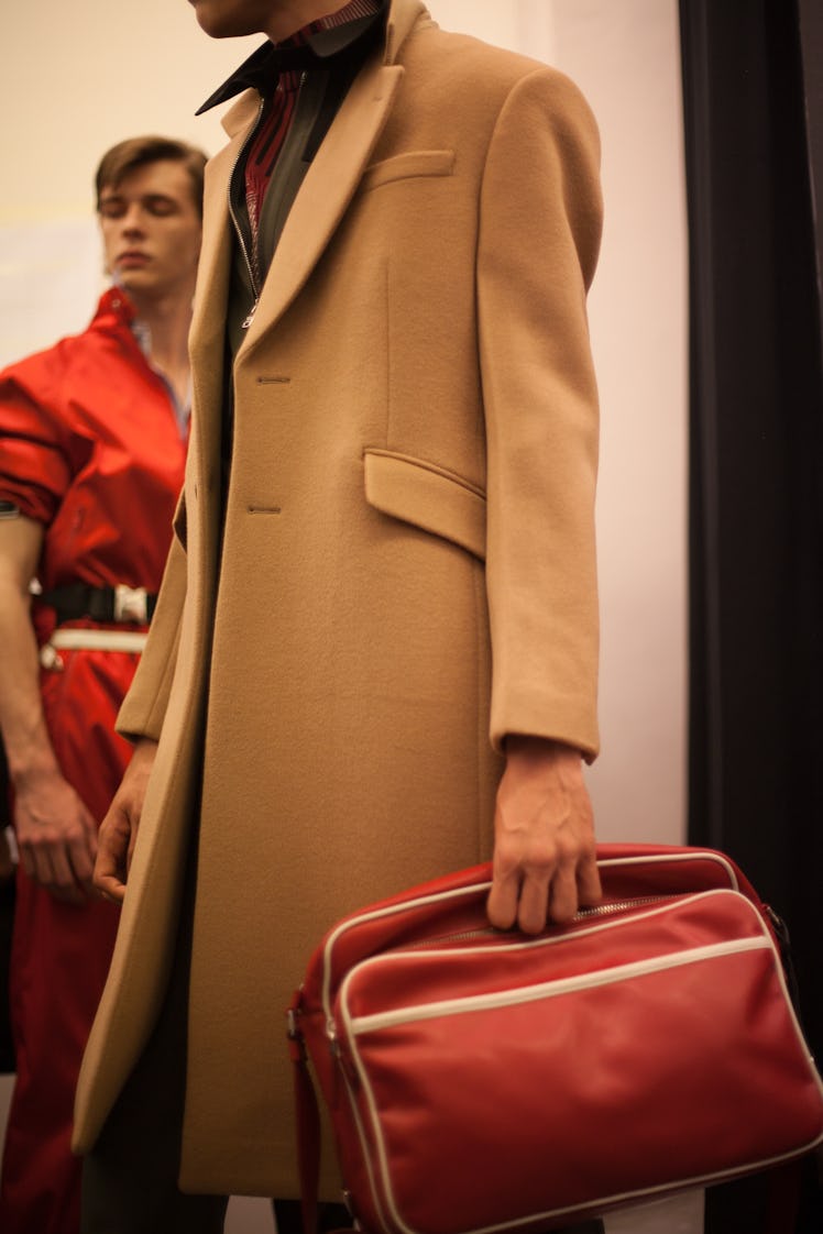 A model in a long camel coat and a red bag at the Prada Spring/Summer 2017 show