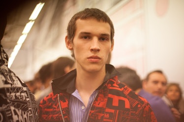 A portrait of a model in a black-red jacket and striped blue shirt at the Prada Spring/Summer 2017 s...