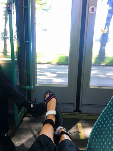 A woman wearing Prada sandals while sitting on the tram