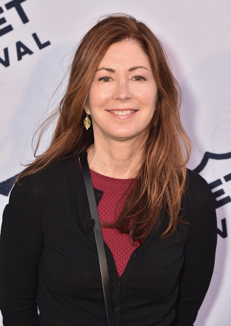  Dana Delany at a red carpet wearing a black long-sleeved shirt, with a red shirt under it, with gol...