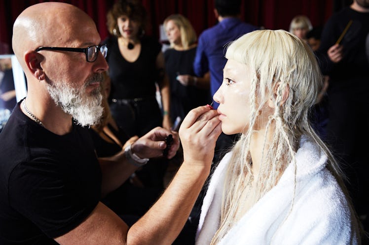 A makeup artist getting a model's makeup done backstage at Iris Van Herpen's 10th Anniversary Fashio...