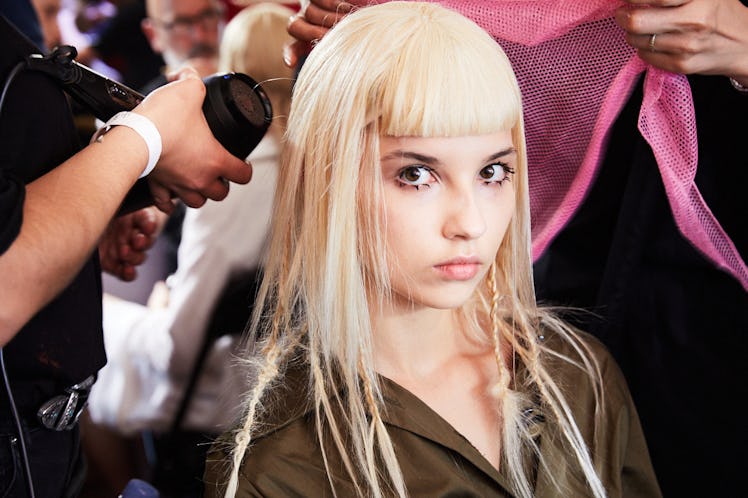 A blonde model getting her hair done backstage at Iris Van Herpen's 10th Anniversary Fashion Show