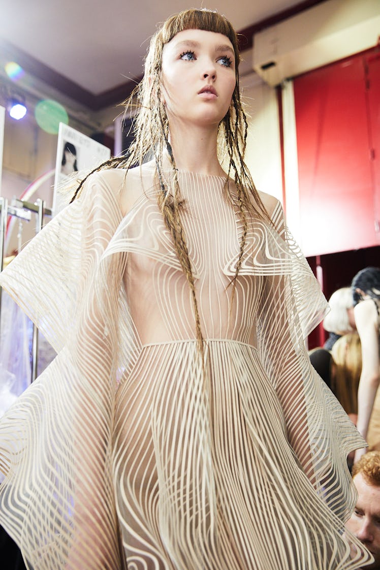 A model in a striped translucent dress backstage at Iris Van Herpen's 10th Anniversary Fashion Show