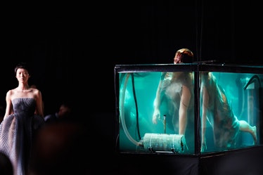 A model walking during Iris Van Herpen's 1oth Anniversary Fashion Show and a model in a water box