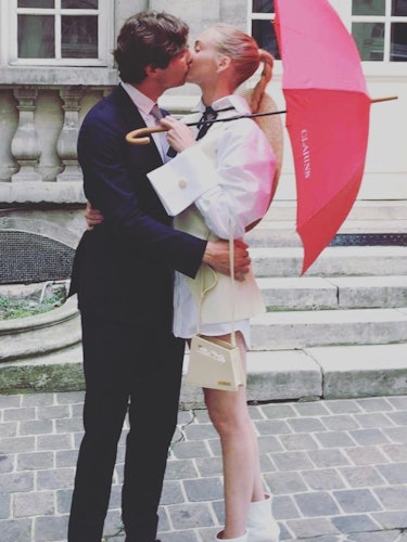 Courtin-Clarins wearing Jacquemus tunic and a straw hat while kissing her partner on their wedding d...