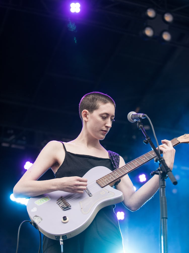 Franke Cosmos performing in a black dress with a guitar at the Pitchfork Music Festival
