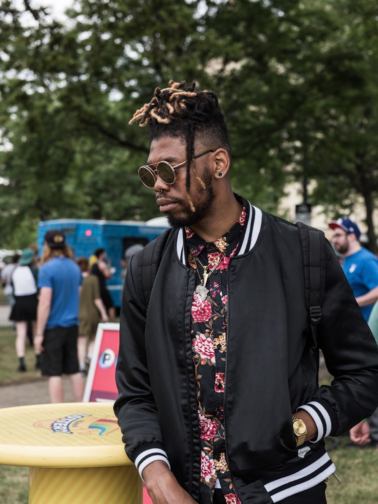 A man in a black-white bomber jacket and floral top at the Pitchfork Music Festival
