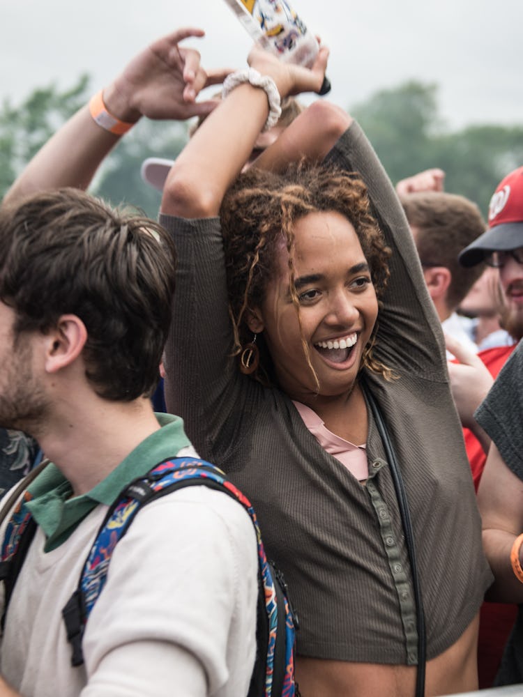 A woman in a brown shirt smiling and dancing with her hands up at the Pitchfork Music Festival
