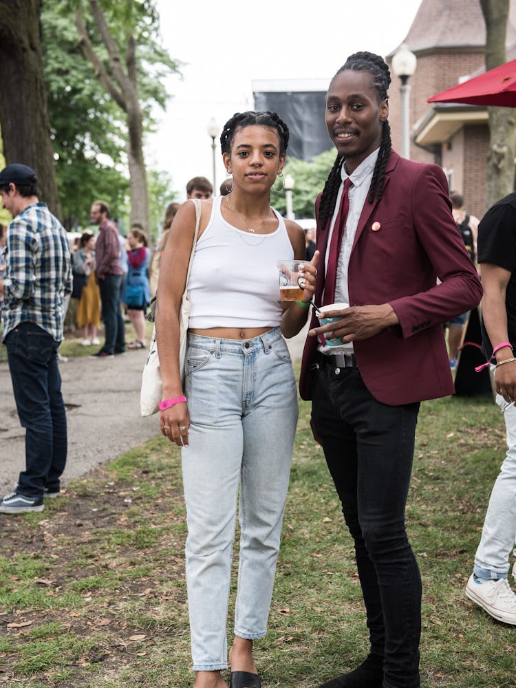 A woman in a white top and blue denim jeans and a man in a red blazer and black pants at the Pitchfo...