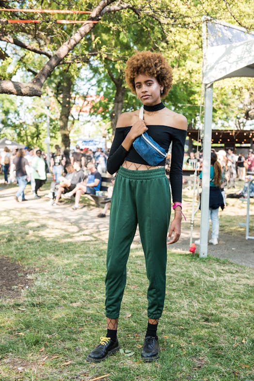 A woman in a black top and green sweatpants attending the Pitchfork Music Festival