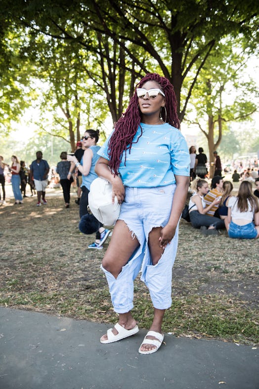 A woman in a light blue top and ripped blue denim jeans attending the Pitchfork Music Festival