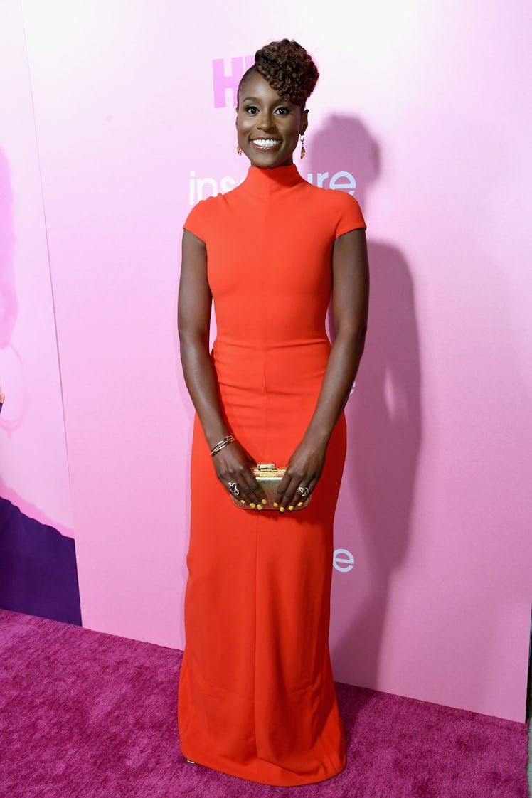 Issa in a long orange gown and a gold clutch at the premiere of Insecure