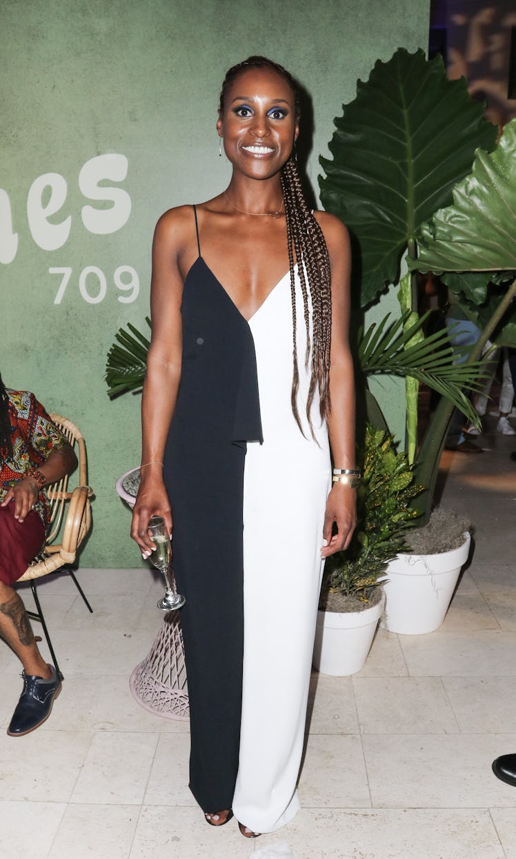 Issa Rae in a half white half black long dress, sporting a long side ponytail 