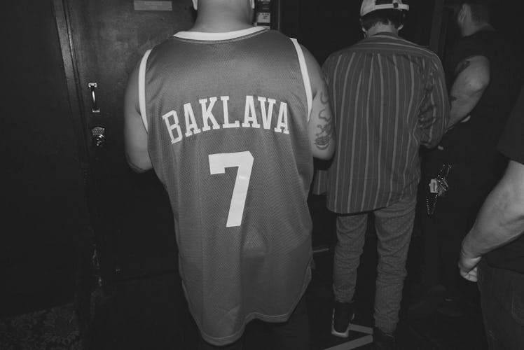 Action Bronson wearing a basketball shirt with "Baklava #7" text sign on the back