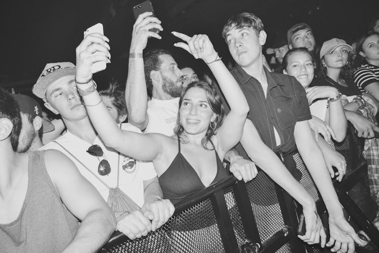 A girl in crowd recording the concert of Action Bronson with her mobile phone