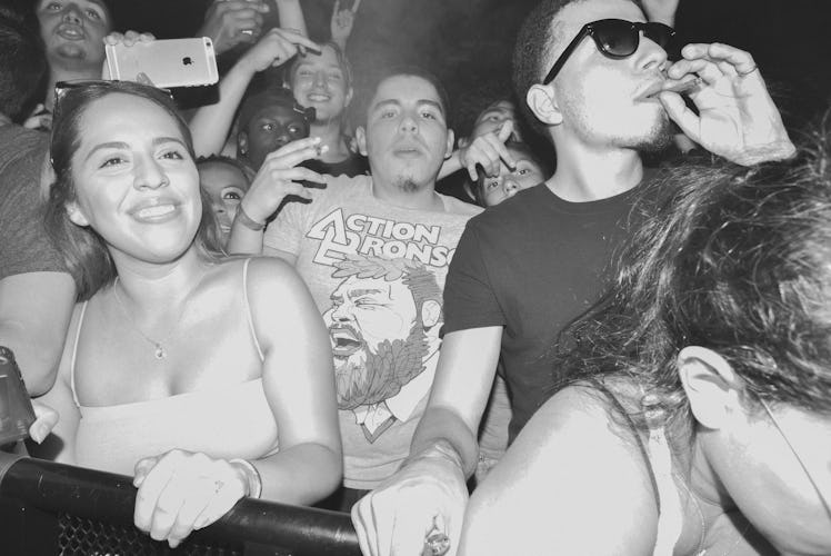 A boy smoking a cigarette at Action Bronson's concert