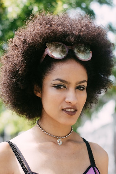 A woman with and afro and sunglasses in her hair wearing eyeliner above her lid at the Afropunk Fest...