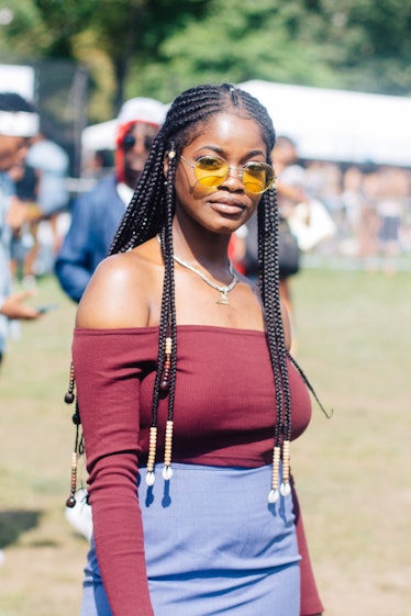 A woman with braids and beads in her hair, and an off-the-shoulder maroon top at the Afropunk Festiv...
