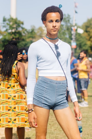 A person with an afro and a comb in their hair, a white long-sleeved tee and denim shorts at the fes...