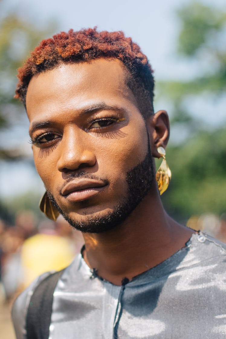 A man with a short hair and dangling gold earrings  looking directly at the camera at Afropunk Festi...