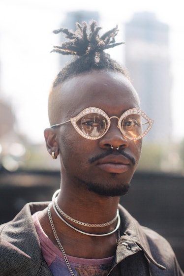 A man with a dreadlock ponytail, yellow sunglasses and a septum piercing at Afropunk Festival