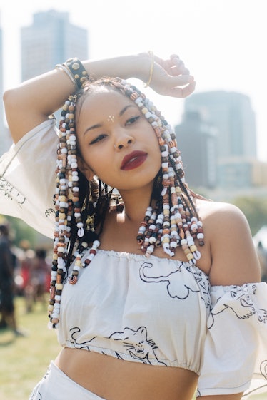 A woman with beads in her hair and a white puffer-sleeved crop top with tigers on it 
