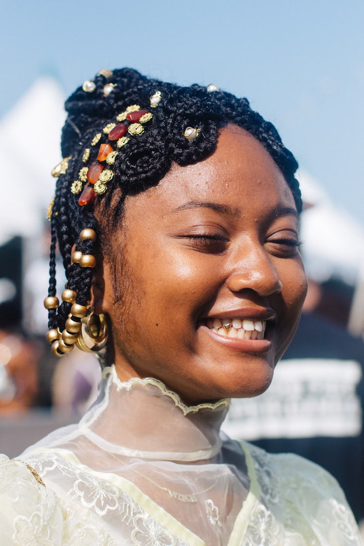 A woman beads in her hair, smiling with her eyes closed at the Afropunk Festival