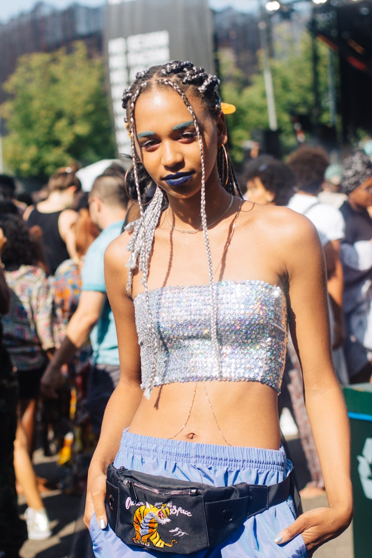 A woman with blond braids and teal lipstick wearing a sequined, cropped, strapless top at the festiv...