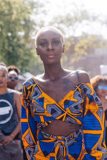 A woman in a yellow and blue matching set and a blonde buzz cut at the Afropunk Festival 