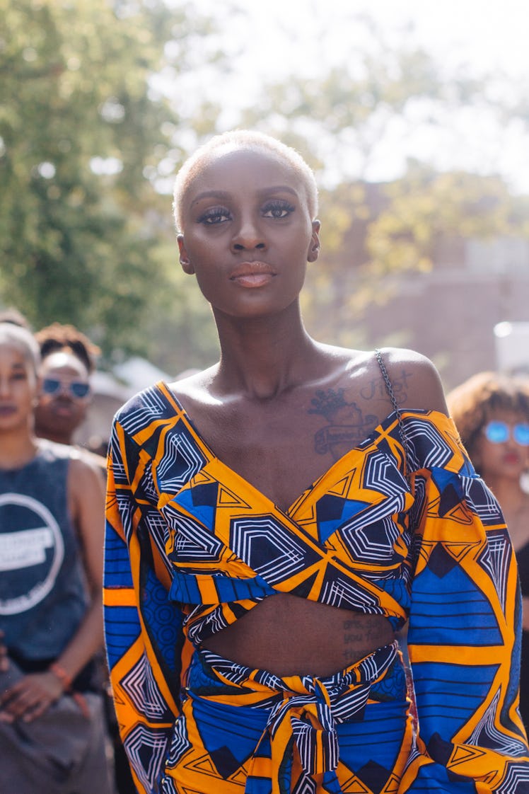 A woman in a yellow and blue matching set and a blonde buzz cut at the Afropunk Festival 