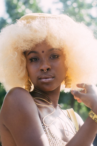 A woman with a blonde afro, golden dangling earrings at the Afropunk Festival