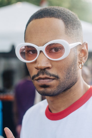 A man with white sunglasses, a gold hoop earring and a nose piercing at Afropunk Festival 
