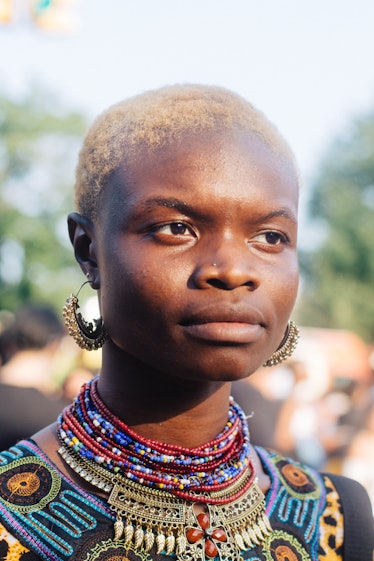 A woman with a blonde buzz cut and golden hooped earrings looking into the distance at the festival 